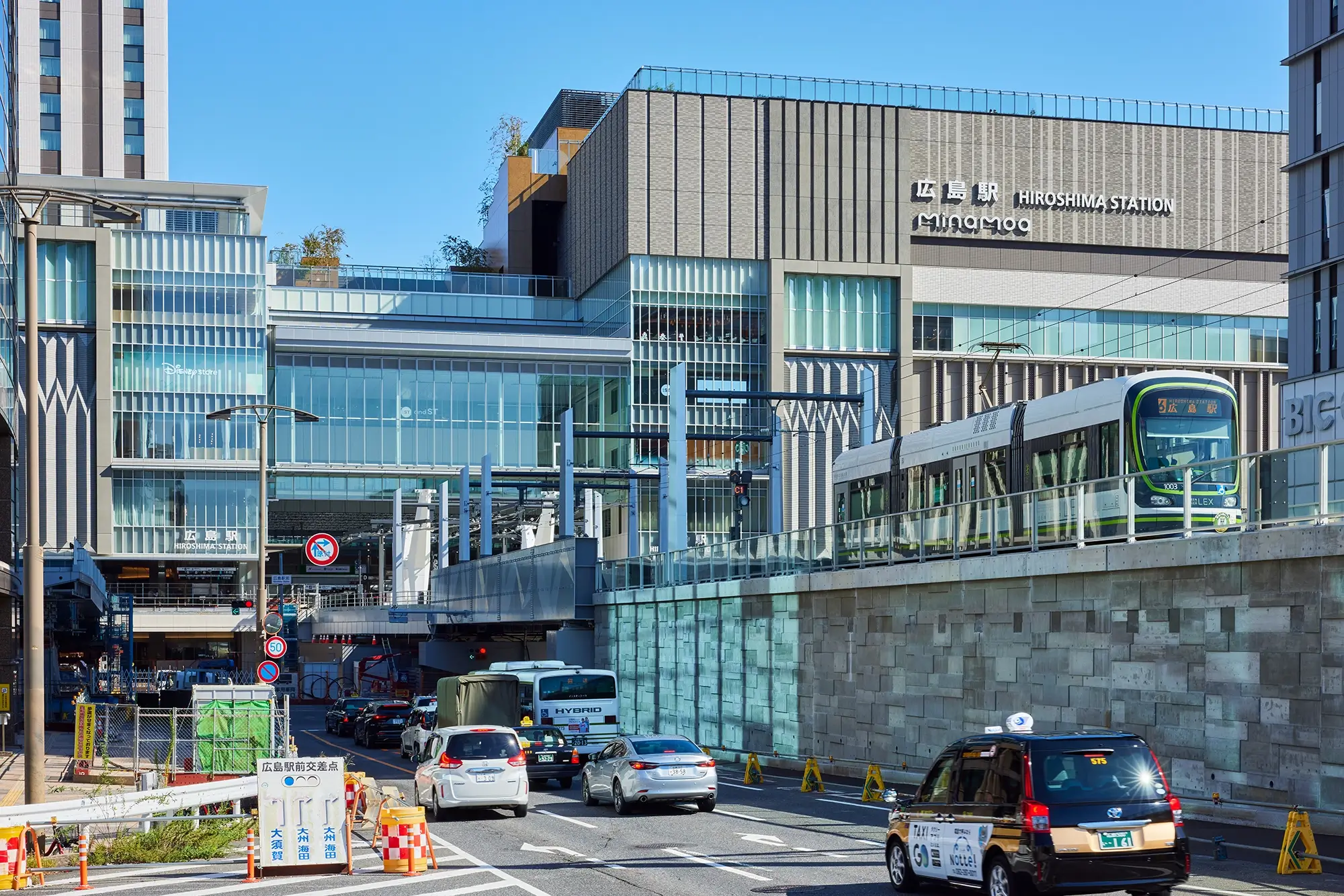 広島駅の新しい駅舎上層階から、路面電車の発着と行き交う人々を見下ろした全景